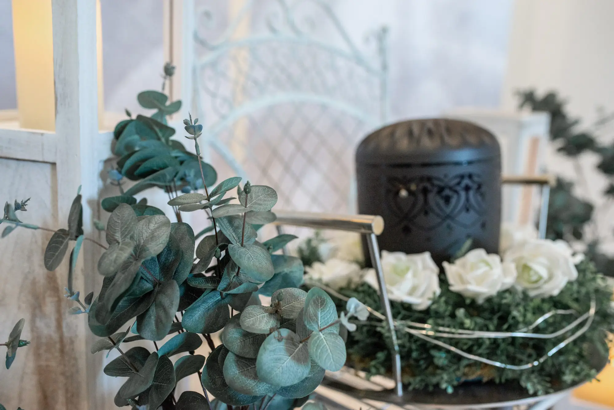 Gedenkfloristik mit weißen Rosen, Eukalyptus und Grabkerze, symbolisch für Trauer und Erinnerung, professionelle Bestattungsvorsorge, respektvolle Trauerbegleitung, Bestattungshaus Horst Fritz Bestattungen.