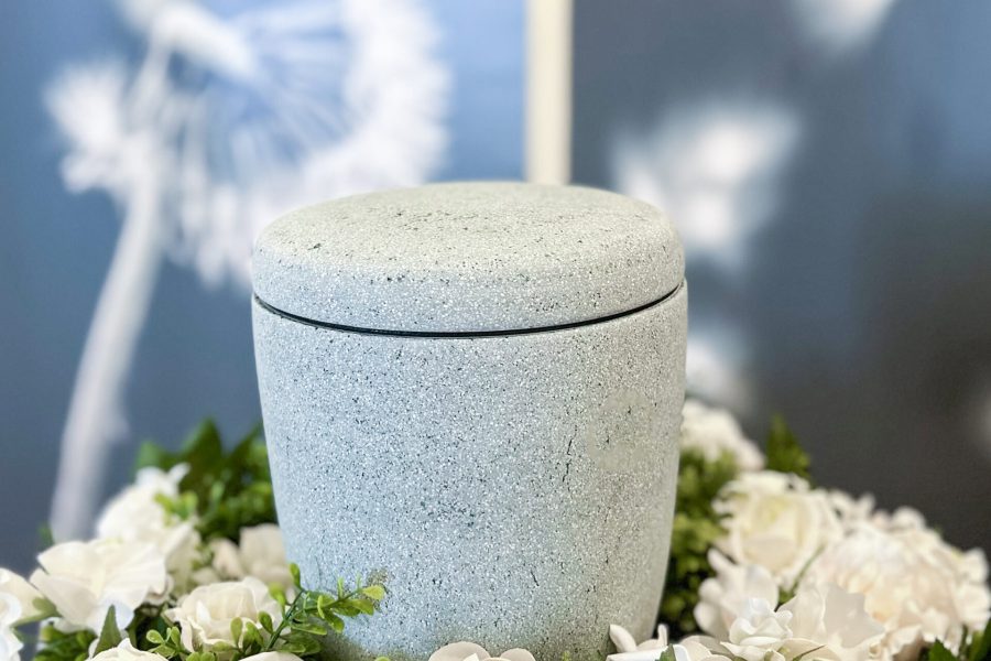 Natürliche Urnenschale aus Stein mit Blumenarrangement, ideal für würdevolle Bestattungen und Trauerfeiern, langlebig und elegant, geeignet für individuelle Abschiedsrituale.