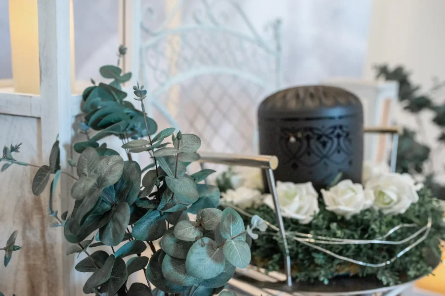 Gedenkfloristik mit weißen Rosen, Eukalyptus und Grabkerze, symbolisch für Trauer und Erinnerung, professionelle Bestattungsvorsorge, respektvolle Trauerbegleitung, Bestattungshaus Horst Fritz Bestattungen.